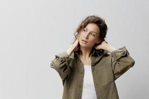 Pensive curly beautiful woman in casual khaki green shirt think about work problems cross hands behind head posing isolated on over white background. People Emotions Lifestyle concept. Copy space photo