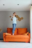 pretty woman in jeans is standing on the couch fun photo