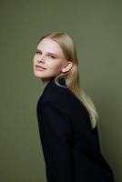 Attractive beautiful bright girl looks into the camera posing in the studio in a suit on a green background photo