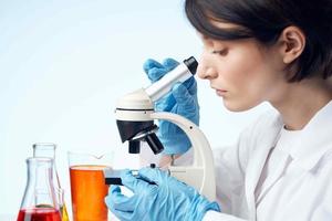 woman laboratory assistant microscope chemical solution research analyzes photo