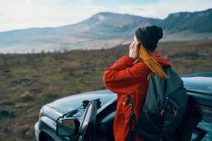 woman hiker in the mountains on nature near the car with a backpack on the back photo