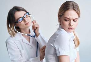 contento mujer médico examinar hembra paciente en blanco camiseta salud modelo foto