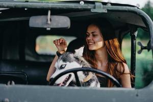 Woman and husky dog happily traveling in car smile with teeth fall walk with pet, travel with dog friend hugs and dances photo