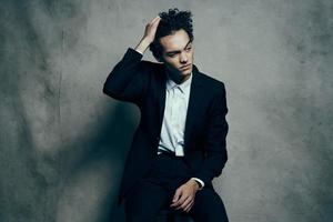 curly haired guy in a suit sitting on a chair fashion modern style jacket photo