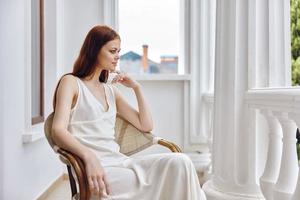 pretty woman with long hair sits in a chair on the terrace photo