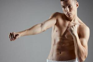 Boxer con un desnudo torso formación en un gris antecedentes abdominales cubitos en el estómago Copiar espacio foto