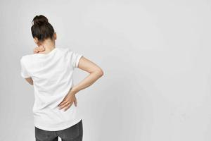 woman in white t-shirt holding her lower back health problems photo