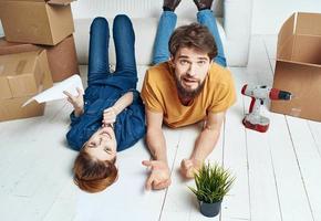 To women men on a wooden floor with boxes and a flower in a pot photo
