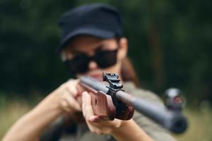 Woman on nature Blowing weapon sight hunting target black cap photo