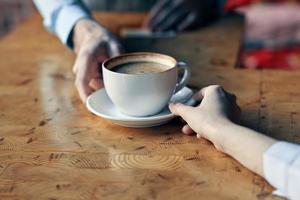 el cocinero sirve el cliente un taza de café con un platillo en el mesa y un restaurante bebida foto