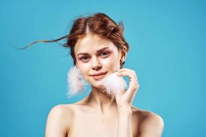 smiling woman naked shoulders earrings posing blue background photo