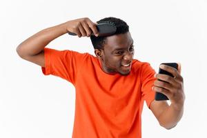 African man with a comb in his hands hair care phone in his hands photo