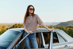 A young woman driver looks out of the car at the autumn landscape and smiles satisfactorily photo