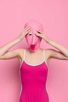 Crazy woman in pink fish head costume poses on pink studio background, provocative Halloween costume photo