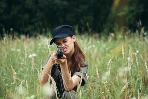 mujer soldado dirige el bozal de un pistola adelante visión caza apertura Fresco aire foto