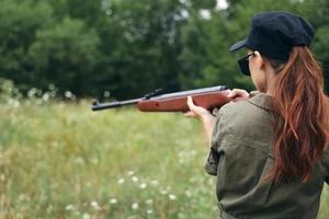 Woman on outdoor Weapon in hand sight aim lifestyle rear view green overalls green photo