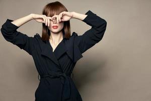 woman in a black coat holds hands in front of her eyes photo