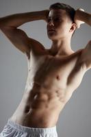 athlete with cubes on his stomach holds his hands behind his head photo