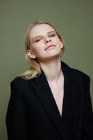 Attractive beautiful bright girl smiling looks into the camera posing in the studio in a suit on a green background photo