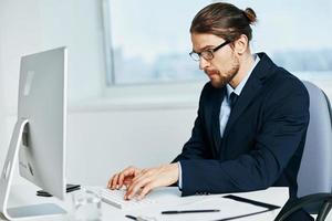 male manager sitting at a desk in front of a computer technologies photo