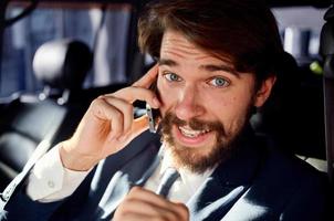 bearded man talking on the phone in a car trip photo