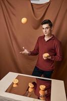 Handsome man tossing orange table mirror studio photo