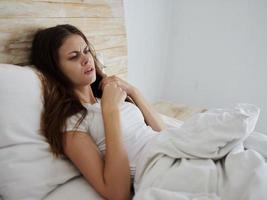 enojado mujer mentiras en cama insatisfecho con alto temperatura foto