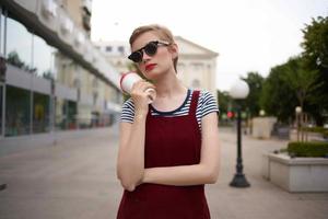 mujer en el calle hablando en el teléfono vistiendo lentes vaso con bebida Moda foto