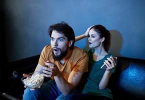 frightened woman and man watching a movie in the evening in front of tv on the couch photo