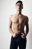 Guy on a light background in trousers naked torso cropped view photo