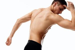 man in shorts and with his hands raised up bent to the side on a light background cropped view photo