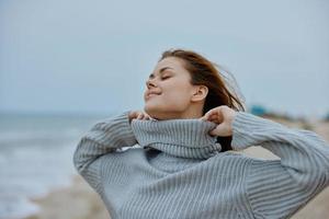 beautiful woman in a sweater flying hair by the ocean tourism Lifestyle photo