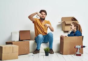 Man and woman boxes with things white sofa interior moving room photo