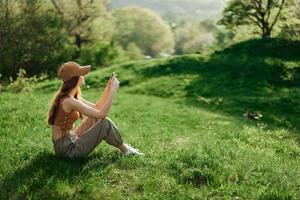 A woman sitting on the green grass in a park in summer against a landscape of trees, the work of a freelancer and blogger photo