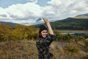 alegre mujer con un médico máscara en su mano en el bosque seco césped montañas naturaleza foto