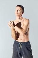 a naked athlete in shorts on a light background gestures with his hands biceps muscles photo