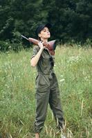 mujer en al aire libre con un pistola en su hombro verde mono viaje estilo de vida armas foto