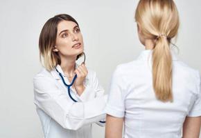 A nurse doctor in a medical gown explains something to a patient in a white T-shirt photo