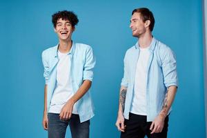 curly guy in a blue shirt and a blond man on a blue background communication friends fun photo