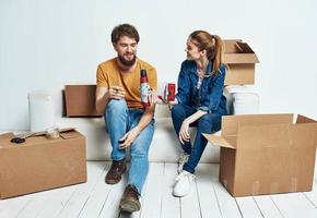 hombre y mujer sentar en blanco sofá cajas con Moviente estilo de vida cosas foto