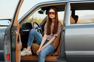 un mujer conductor en Gafas de sol detenido el coche en el la carretera en un pktkshestvie y es descansando mirando a un hermosa ver foto