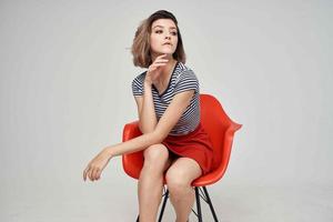 woman with glasses sitting on the red chair light background Lifestyle photo