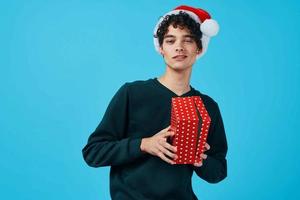 cute guy wearing santa hat gifts party blue background photo