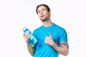 hombre en un azul camiseta con un botella de agua en su mano en un blanco antecedentes Copiar espacio foto