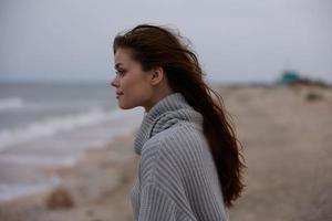 portrait of a woman in a sweater flying hair by the ocean tourism Lifestyle photo