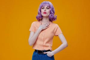 Beautiful fashionable girl hand gestures purple hair fashion clothes yellow background unaltered photo
