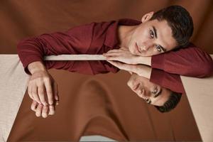 handsome man lies on a table with a mirror and fabric background model photo