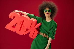 Positive young woman green dress afro hairstyle dark glasses twenty percent in hands studio model unaltered photo