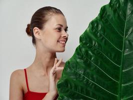 happy woman with green leaf of palm tree red t-shirt light background model photo