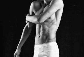 man in white panties such black body fitness posing dark background photo